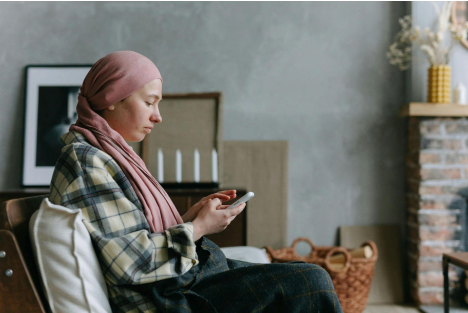 Patient with headscarf using smartphone to access digital health services in a cozy home setting.