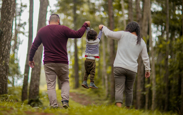 Father and mother lifting their child during a forest walk, symbolizing increased energy and family time after bariatric surgery.